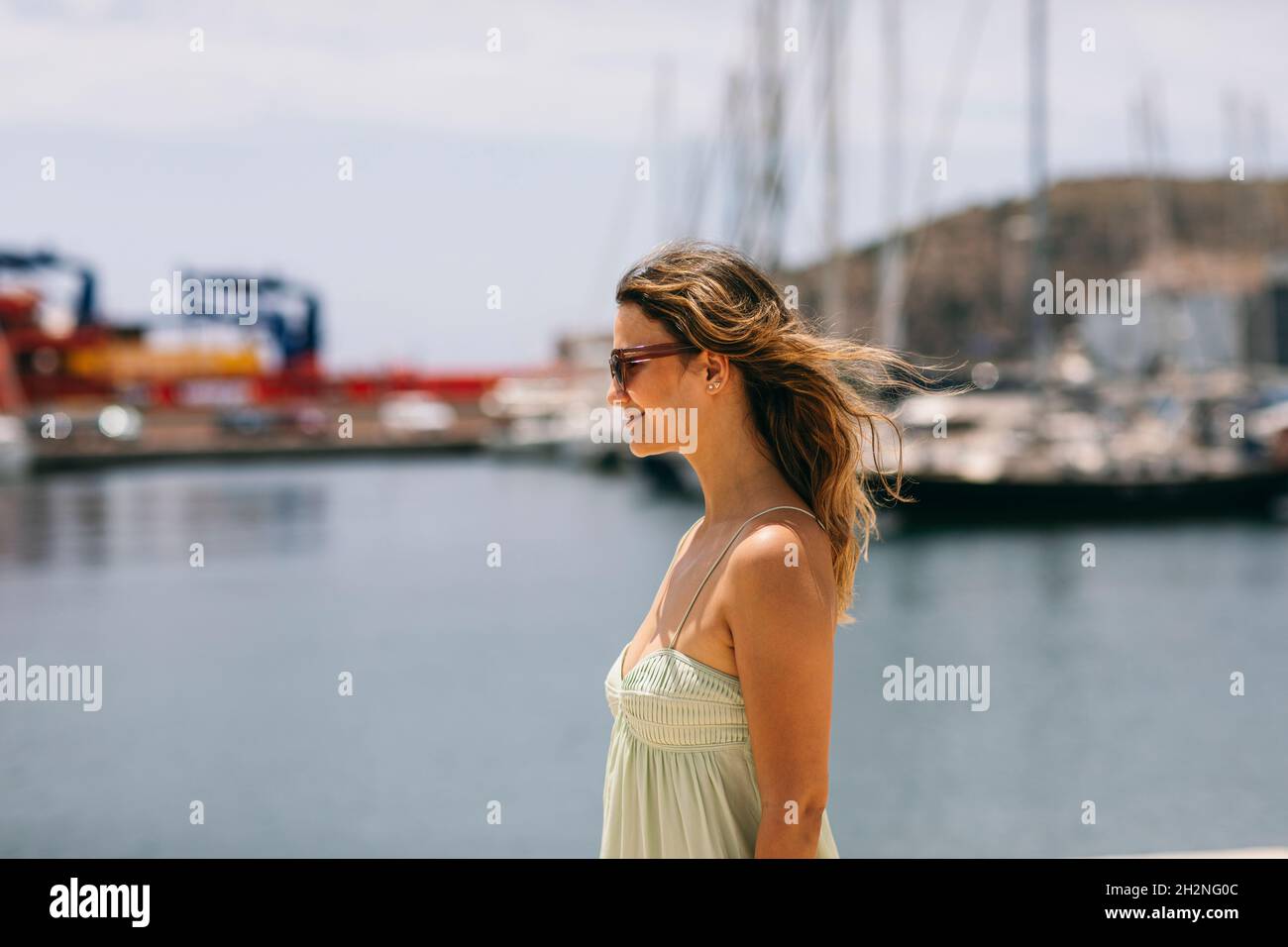 Femme souriante aux cheveux bruns portant des lunettes de soleil le jour du soleil Banque D'Images