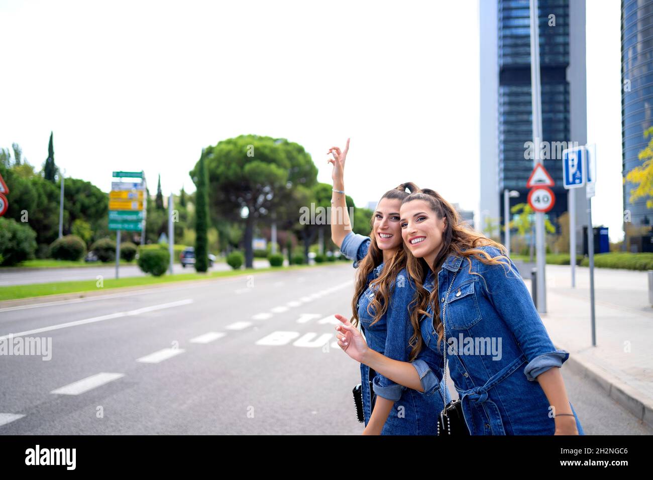 Sœurs jumelles souriantes debout sur la route en ville Banque D'Images
