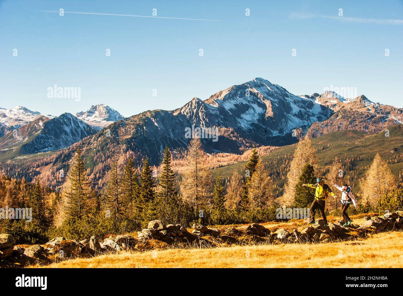 Deux randonneurs qui marchent le long d'un petit étang dans les Alpes Ennstales en automne Banque D'Images