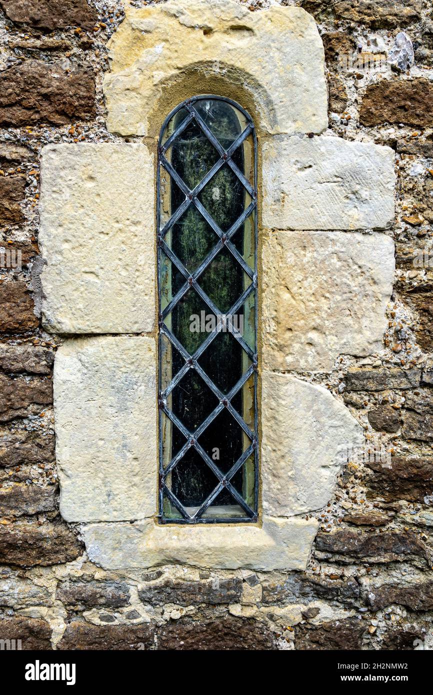 Étroite fenêtre lumineuse au plomb dans le mur de l'église Banque D'Images