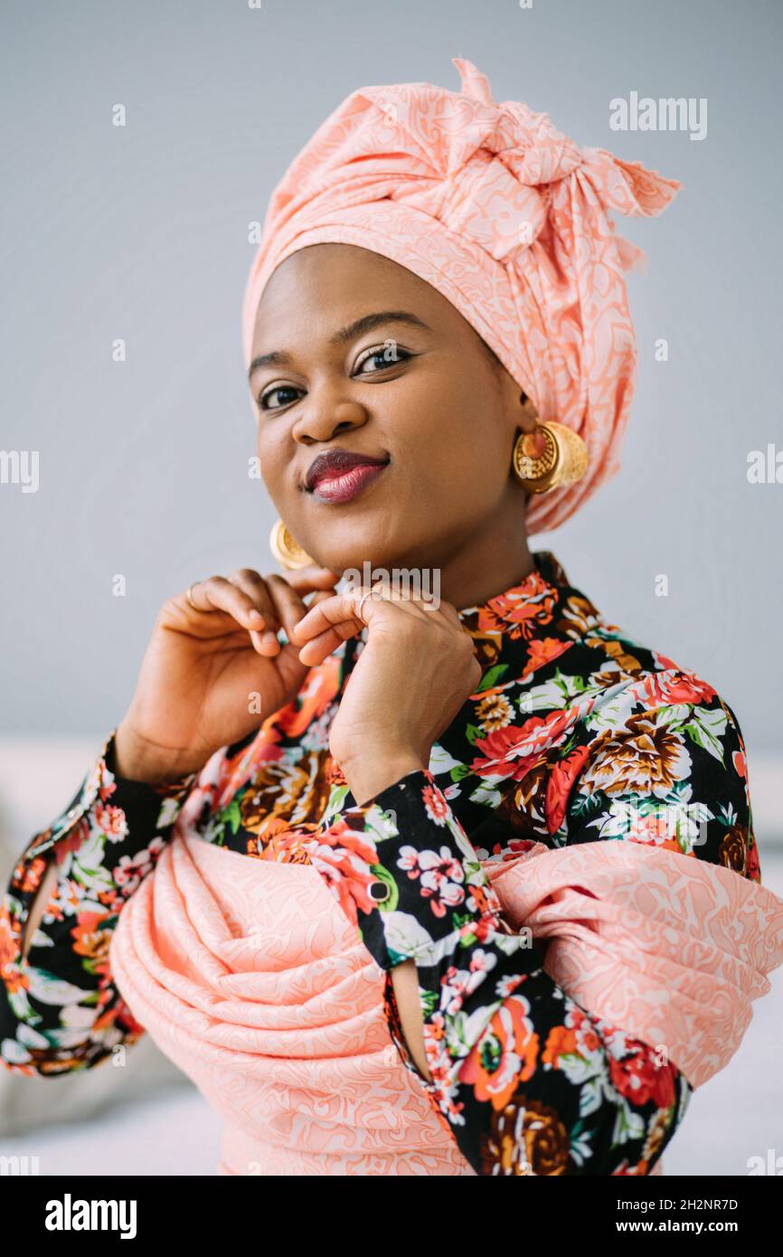 Beauté, ethnie et mode concept.Portrait de la femme africaine.Jolie femme  souriante en robe rose, tissu enveloppé sur la tête et bijoux stylés, sur  fond de studio léger Photo Stock - Alamy