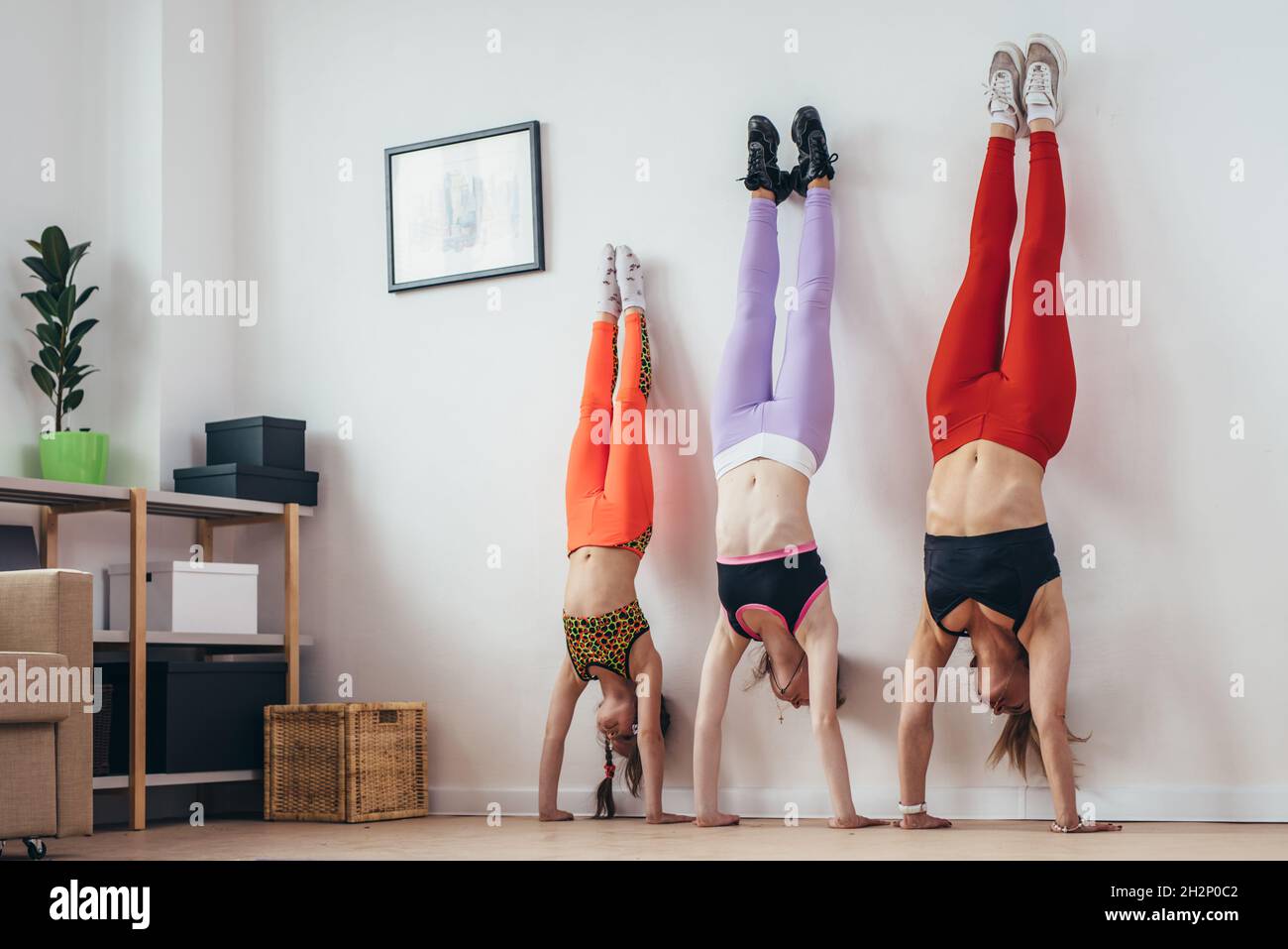 Les femmes qui font la pose de la main près du mur.Mère et filles s'exerçant à la maison, sport, famille. Banque D'Images