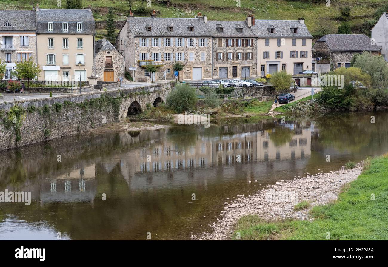 Des maisons en pierre bordent le quai de la rivière Lot dans le village d'Estaing, Occitanie, France Banque D'Images