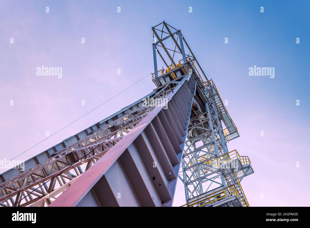 La tour de puits de mine 'Krystyn' dans l'ancienne mine de charbon 'Mical' à Siemianowice, Silésie, Pologne vue d'en dessous contre le ciel bleu avec des nuages roses. Banque D'Images