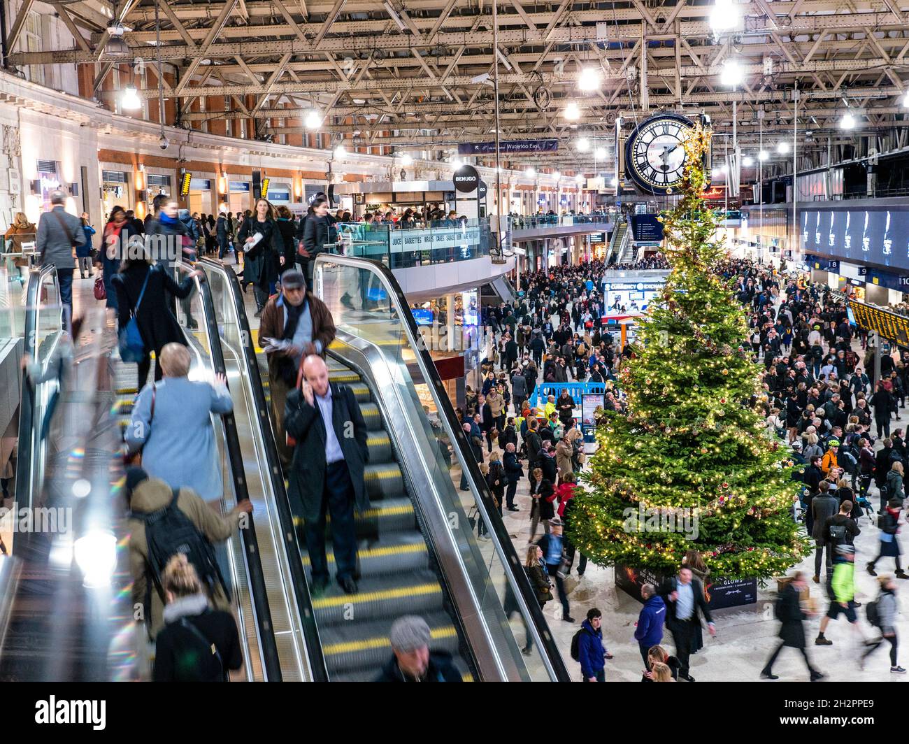 LES FOULES DE NOËL SE DÉPLACENT À LA GARE DE WATERLOO Concourse occupé avec escalier roulant, les acheteurs de Noël flous et les décorations de fête arbre de Noël, Waterloo Station London SE1 Banque D'Images