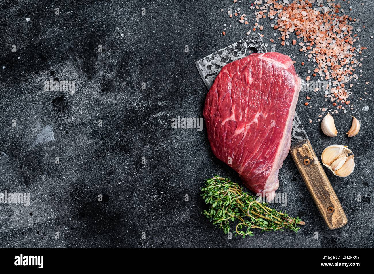 Bœuf cru frais coupé ou steak de chapeau de sirloin sur le couperet de boucher. Arrière-plan noir. Vue de dessus. Copier l'espace Banque D'Images
