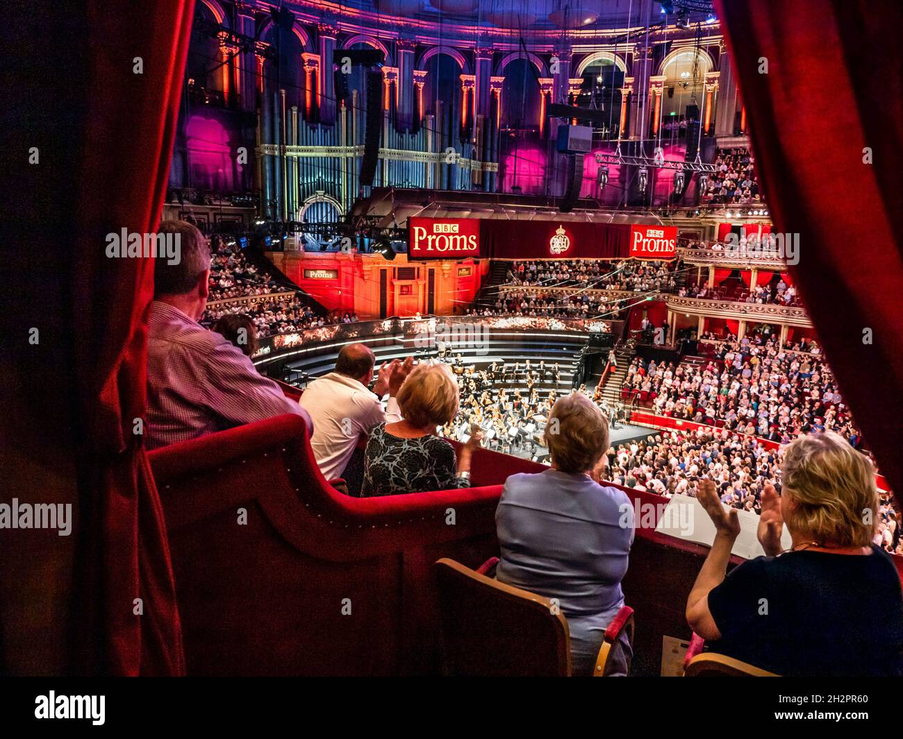 ALBERT HALL APPLAUDIT les performances de BBC PROMS avec le public applaudissant la vue en hauteur, de la boîte privée en velours rouge de luxe au public et à la scène d'orchestre dais derrière Londres Royaume-Uni Banque D'Images