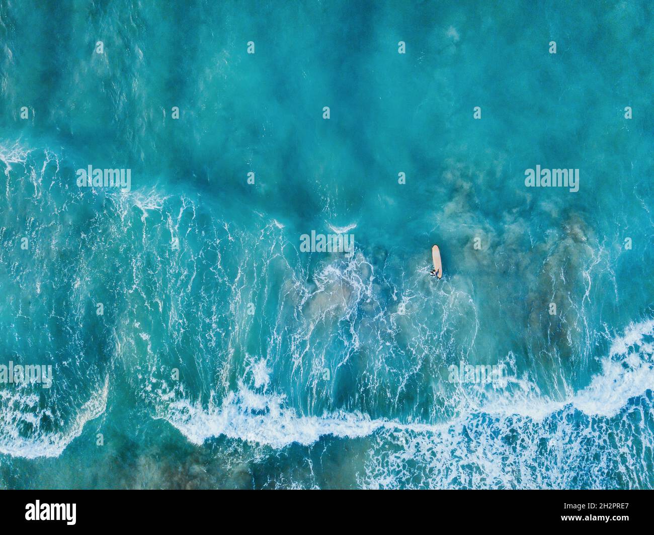 vue aérienne en haut vers le bas du surfeur avec planche de surf dans la vague de l'océan de drone Banque D'Images