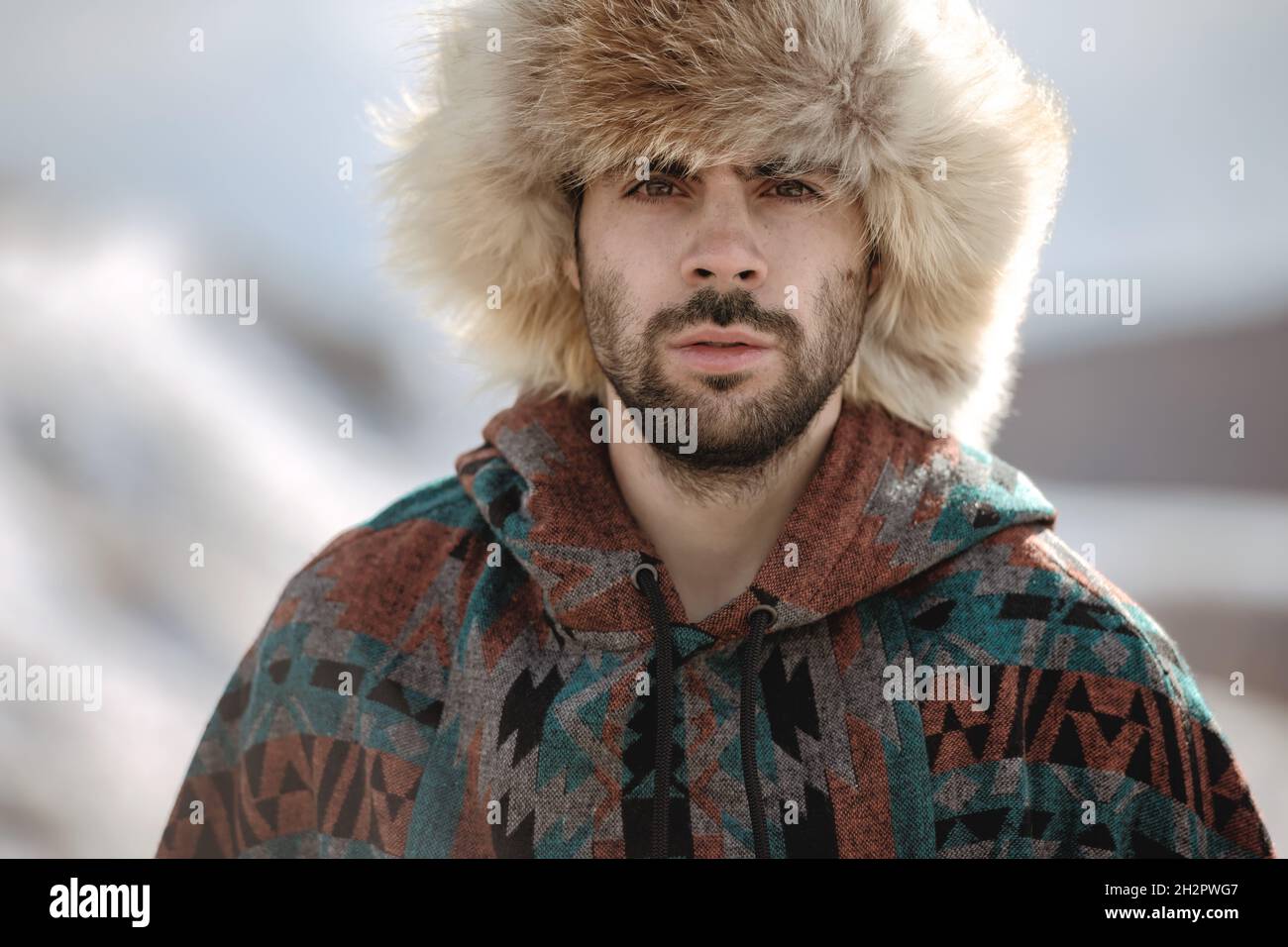 Portrait d'un bel homme hipster barbu dans un chapeau de renard arctique et un poncho Banque D'Images Portrait d'un bel homme hipster barbu dans un chapeau de renard arctique et un poncho Banque D'Images