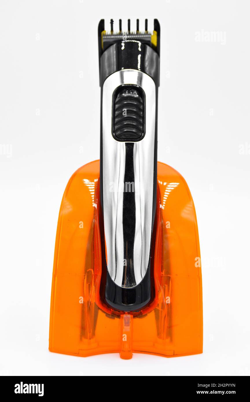 Rasoir électrique sans fil et chromé et chargeur orange, tondeuse cheveux chargée isolée sur fond blanc Banque D'Images