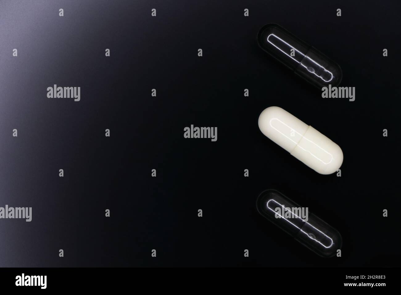 Capsules de gel noir et blanc sur le noir lisse Banque D'Images