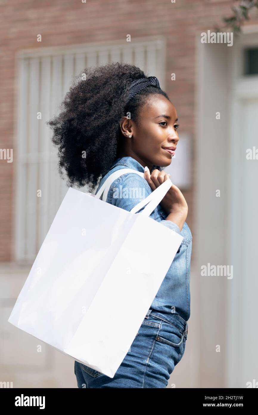 Photo verticale d'une femme africaine marchant avec un sac de shopping en papier Banque D'Images