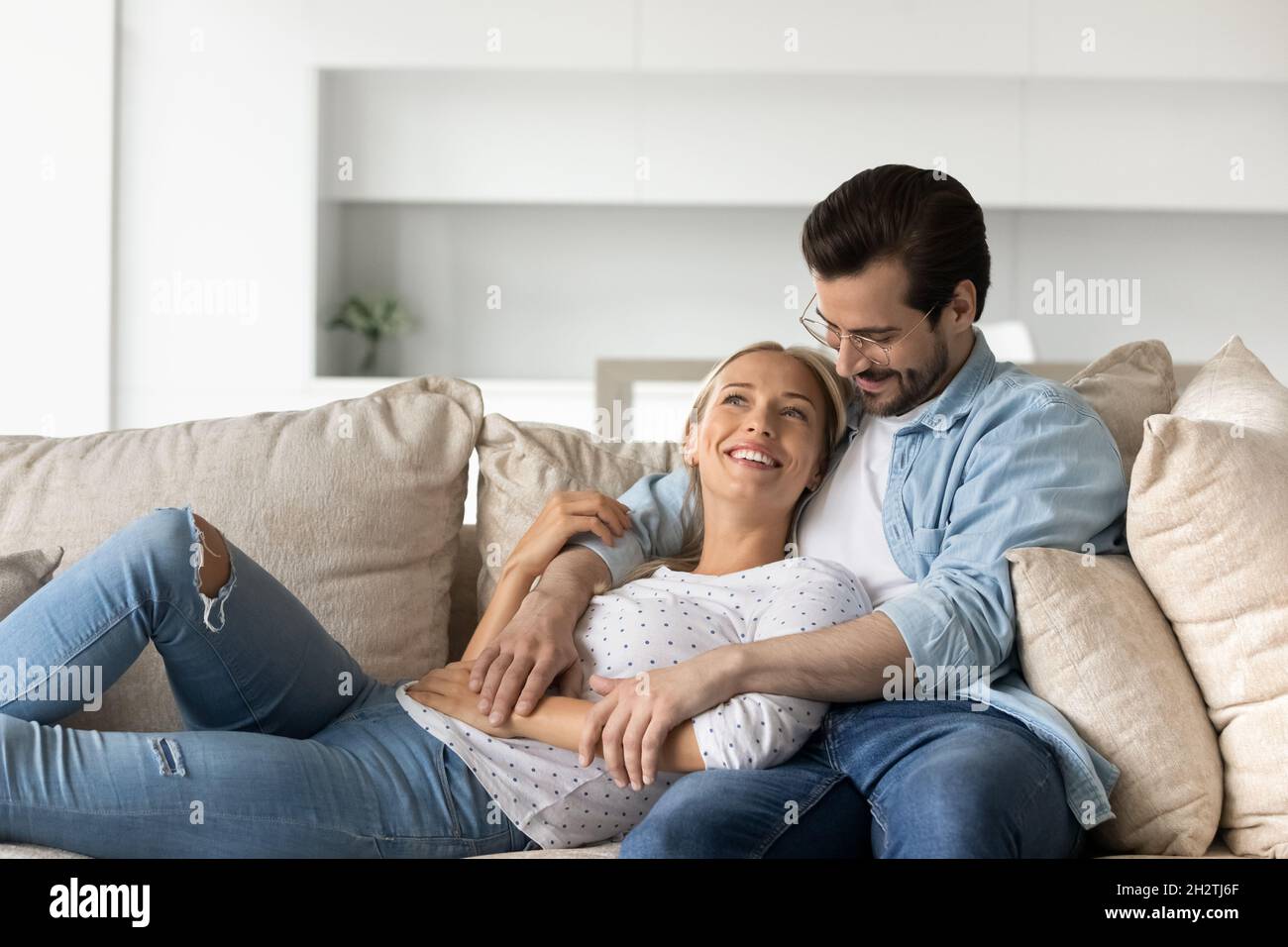 Un couple familial affectueux et joyeux se détendant sur un canapé confortable. Banque D'Images