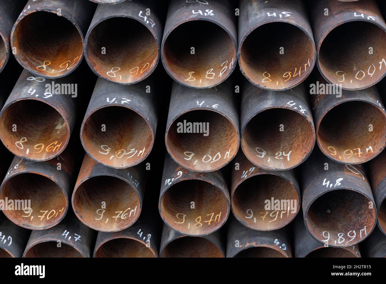 Les tuyaux maetalliques de même diamètre sont bien empilés.Vue des tuyaux depuis l'avant.Contexte pour le fournisseur de produits métalliques. Banque D'Images