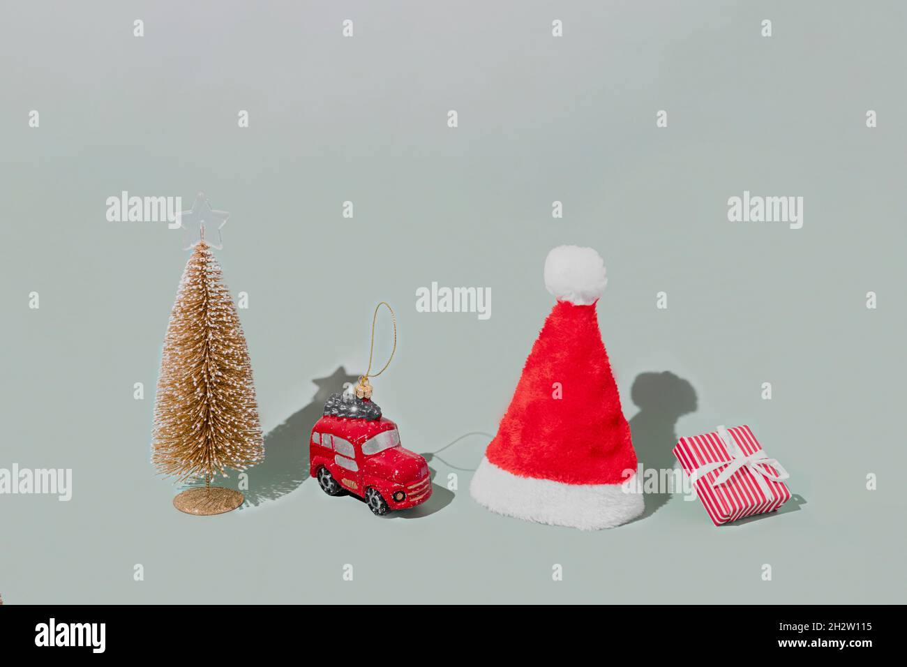 Fond gris avec objets d'attribut de symbole de Noël ou de nouvel an et concept d'éléments symboliques.Boîte cadeau rose avec ruban, petite voiture de taxi rouge Banque D'Images