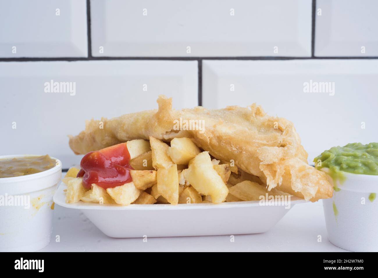 Sheffield, Royaume-Uni – 7 décembre 2017 : poisson et frites traditionnels britanniques avec ketchup, pois mushy ou sauce au curry à Kelham Fisheries Banque D'Images