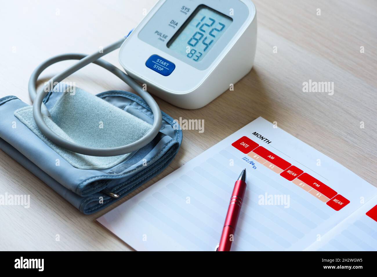 Noter le nombre de pression artérielle dans le carnet après une auto-mesure à l'aide d'un sphymomanomètre numérique portable sur la table. Banque D'Images
