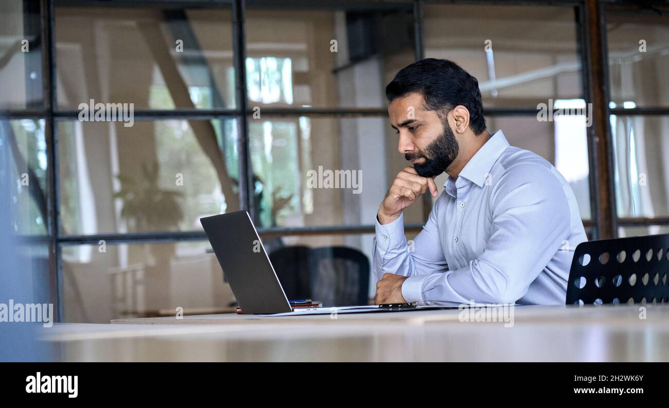 Homme d'affaires indien utilisant un ordinateur portable travaillant au bureau regardant un ordinateur portable. Banque D'Images