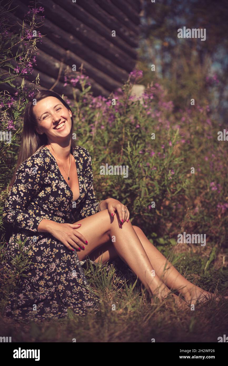 Jeune fille en robe d'été assis dans l'herbe, souriant Banque D'Images