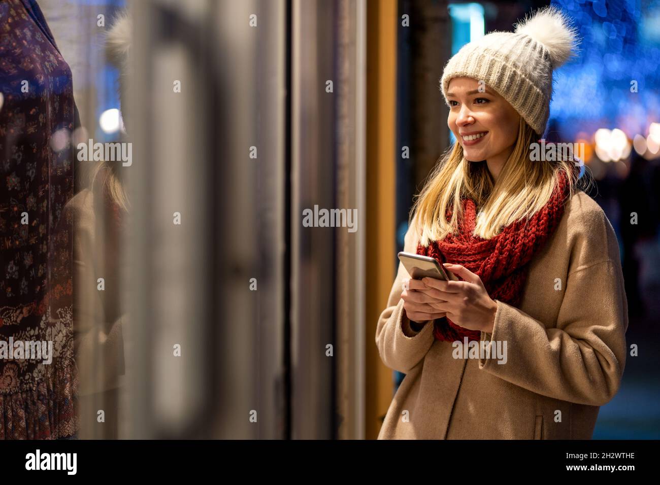 Jeune belle femme utilisant son téléphone mobile surfant sur le net avec un smartphone lors d'une journée d'hiver en ville Banque D'Images