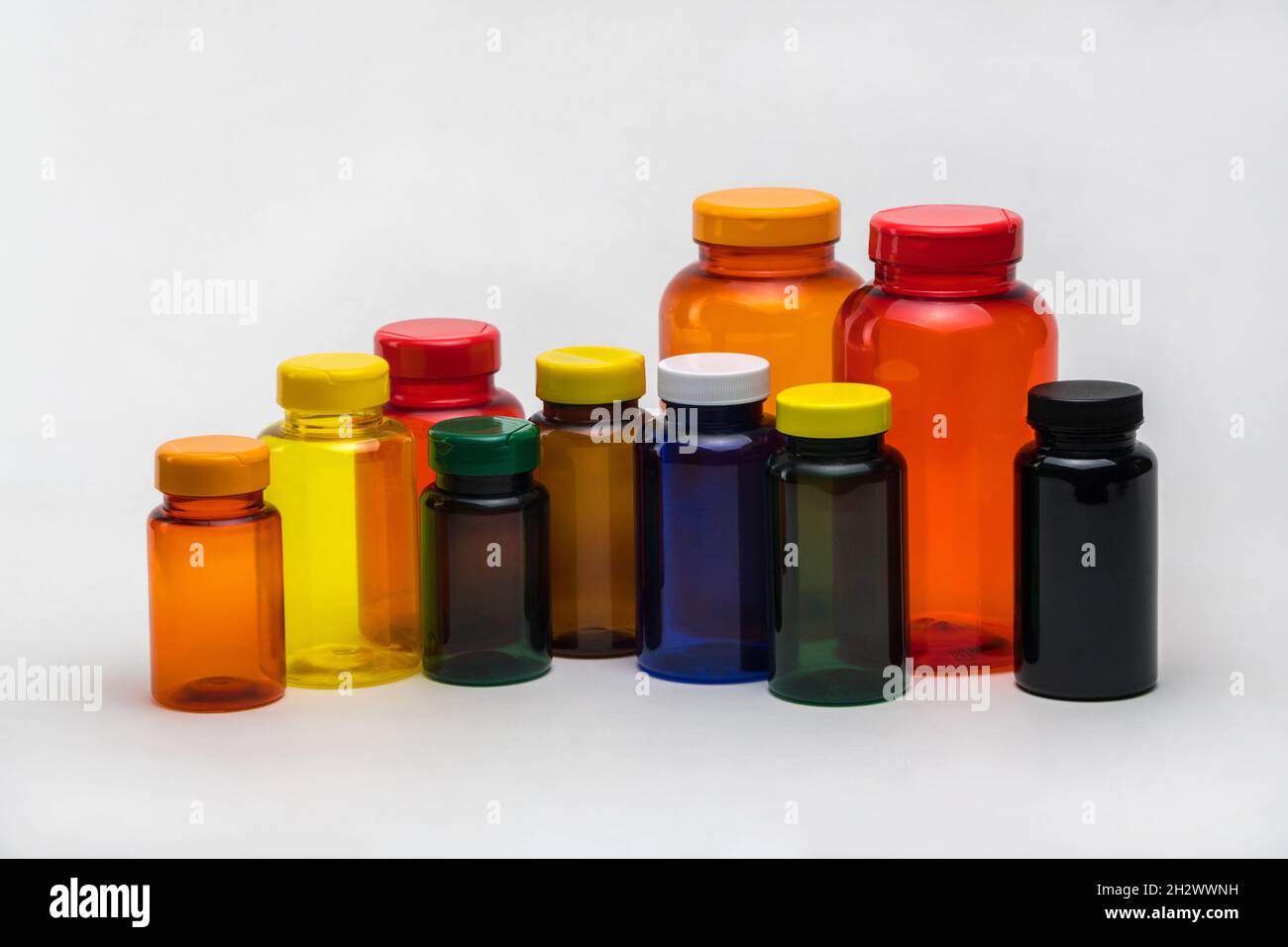 Pots de pilules en plastique transparent multicolores sur fond blanc.Isolé Banque D'Images