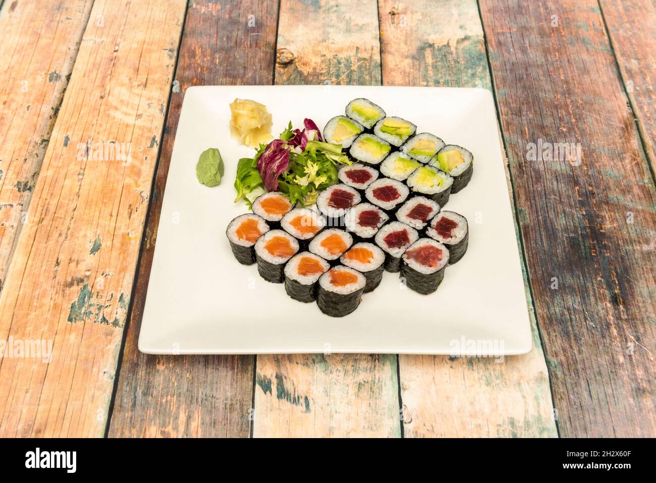 Assortiment de sushis maki de thon rouge, avocat mûr, saumon norvégien, riz blanc au vinaigre japonais, wasabi, ginseng et algues nori Banque D'Images