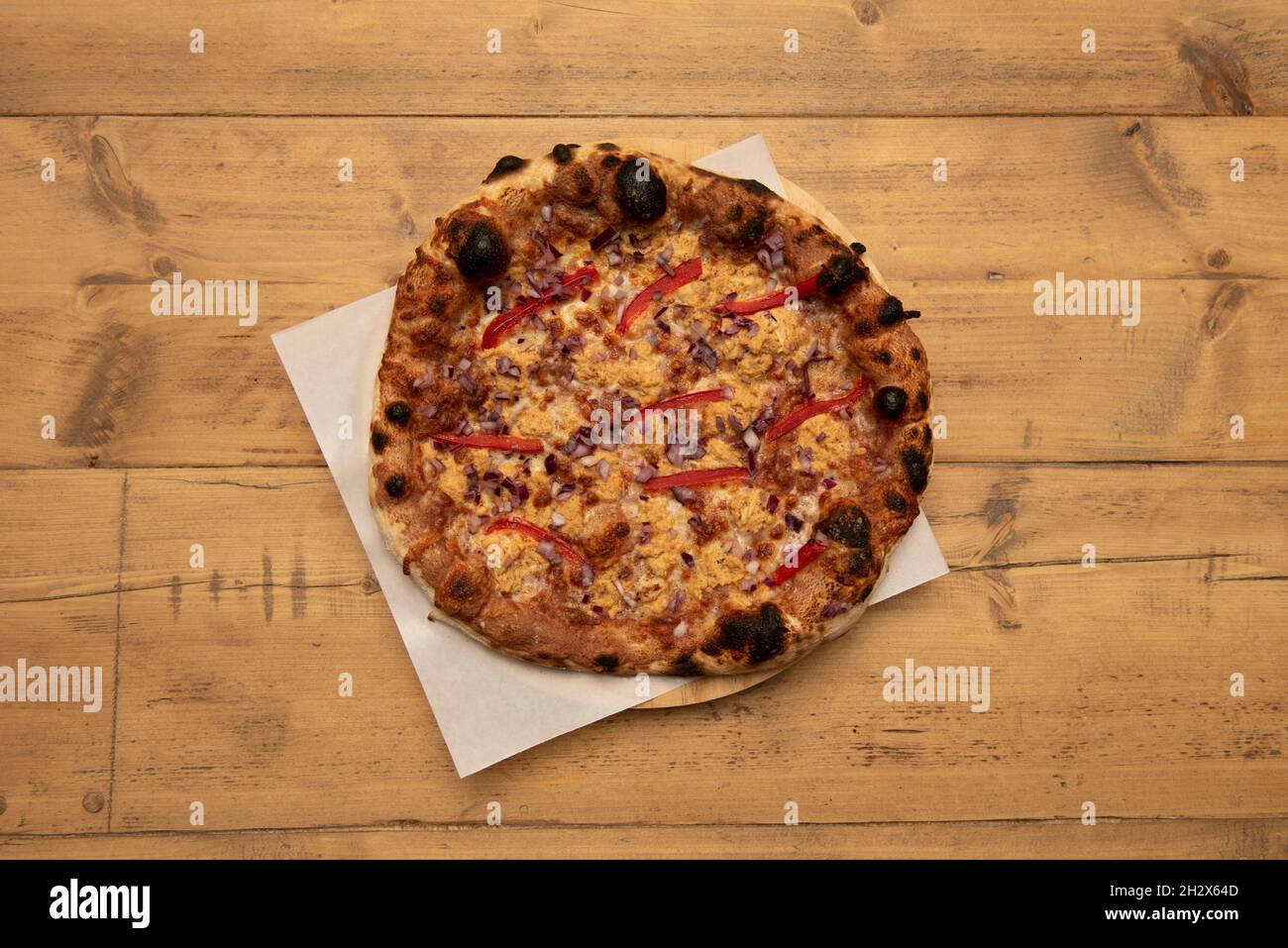 Pizza mexicaine à l'oignon rouge, cheddar fondu, tranches de poivron rouge sur une table en bois Banque D'Images