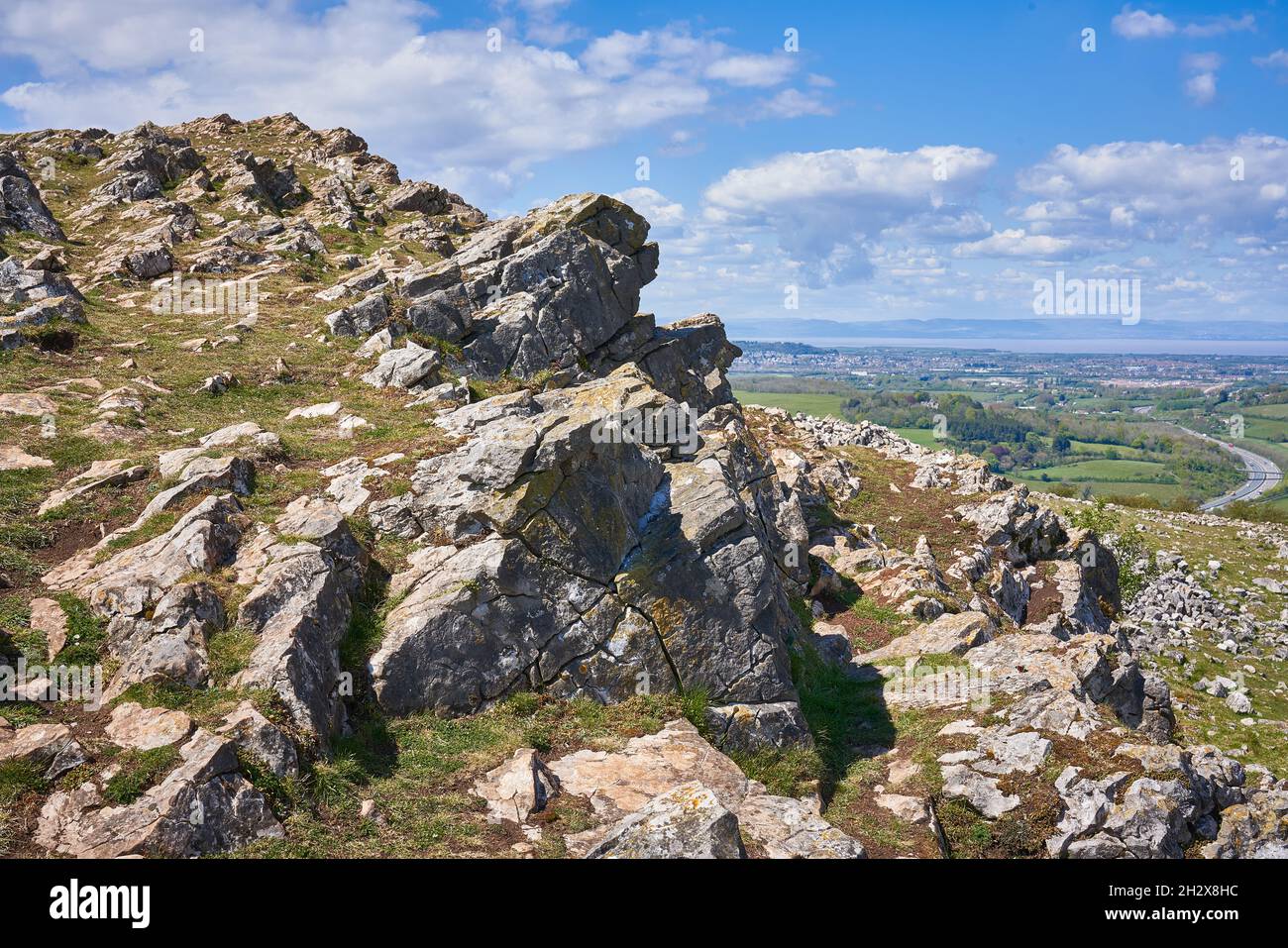 Affleurement de calcaire carbonifère au sommet de Crook Peak sur la limite ouest des Mendips dans le Somerset au Royaume-Uni avec l'autoroute M5 au loin Banque D'Images