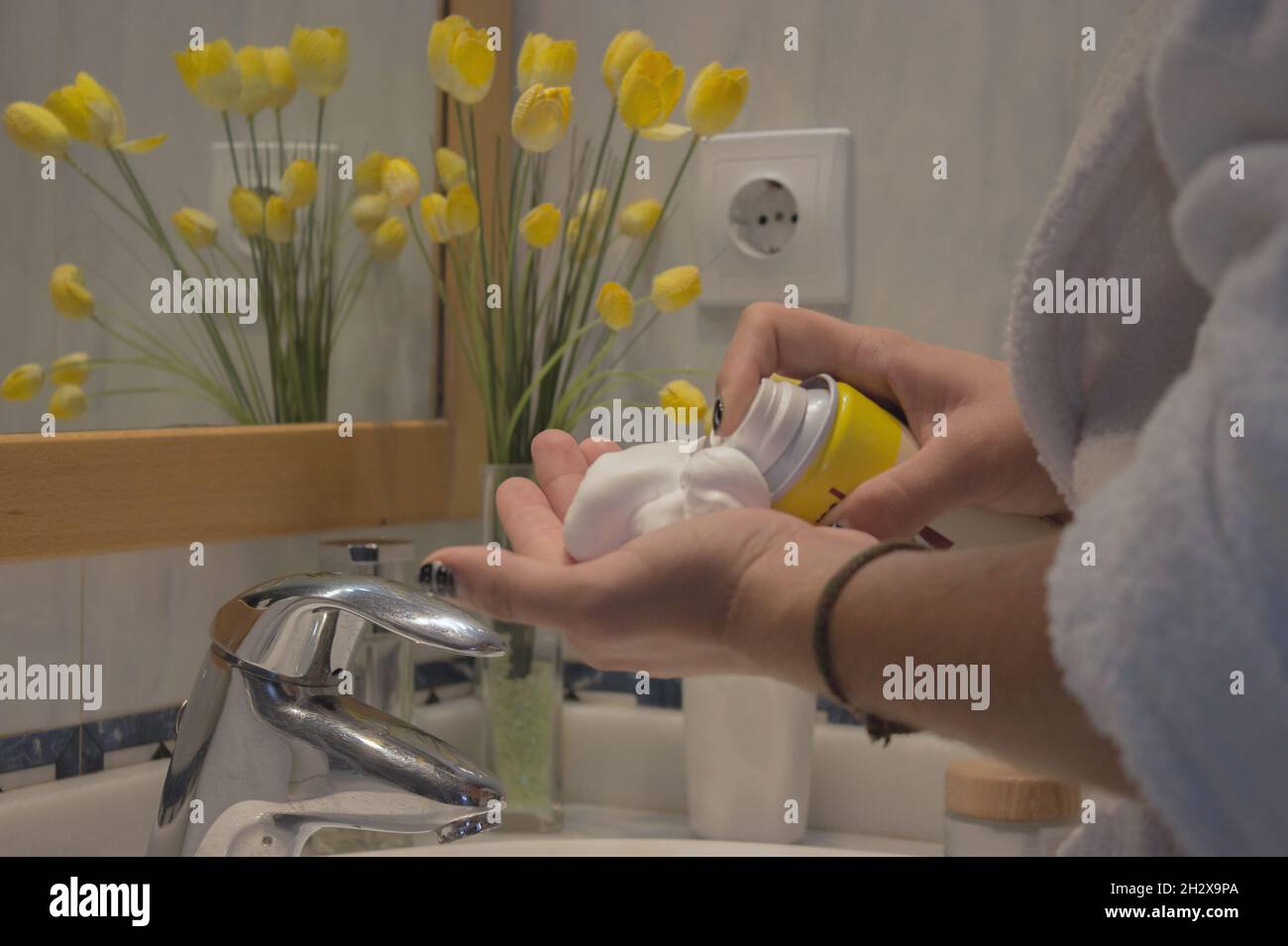 Gros plan jeune homme main dans le peignoir en ramassant la mousse de rasage dans la salle de bains de l'appartement.Concept de spa Beauty Home. Banque D'Images
