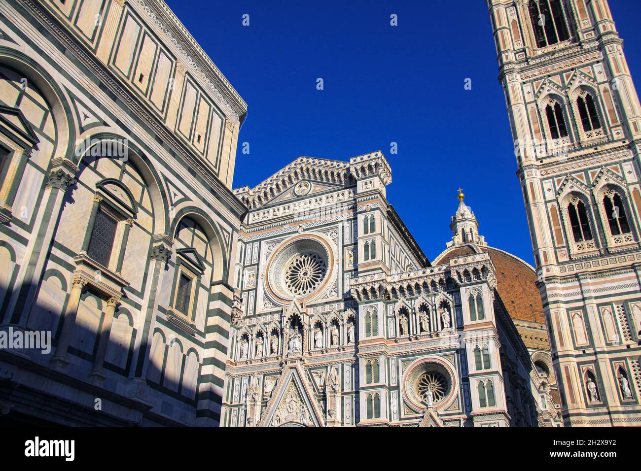 La façade élaborée de la cathédrale Santa Maria del Fiore à Florence, Florence, Italie, avec la Tour de la cloche et le détail du Dôme et bleu profond Banque D'Images