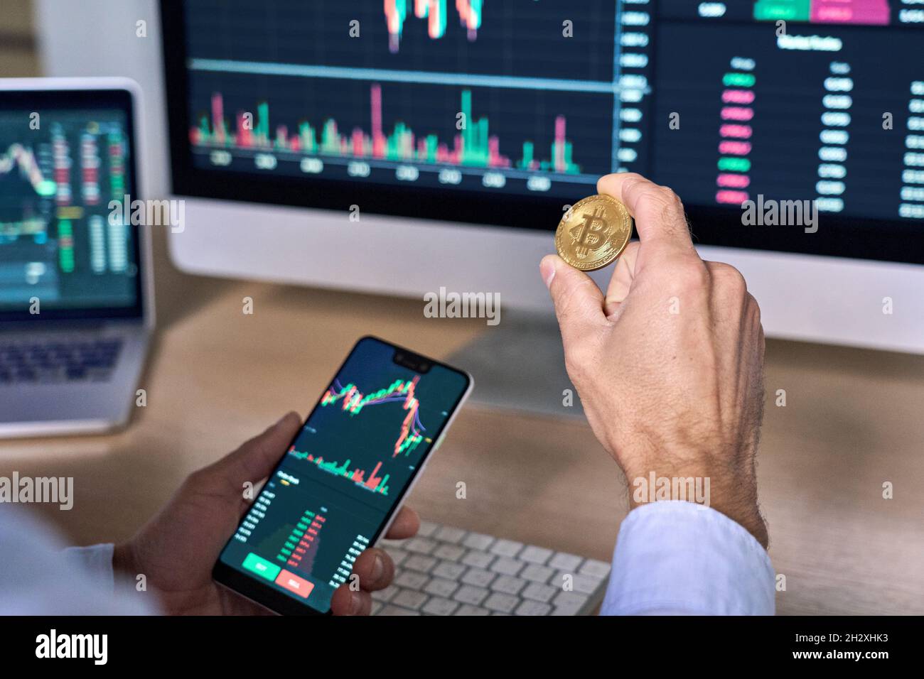 Cypto Trader investisseur tenant le téléphone et la pièce d'achat bitcoin à l'aide de l'application mobile. Banque D'Images