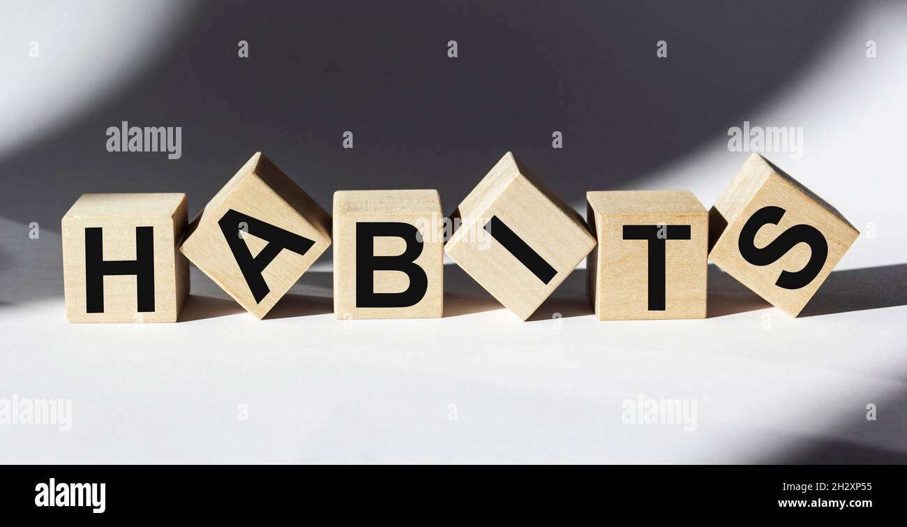 Le mot habitudes écrit sur des cubes en bois et fond blanc Banque D'Images