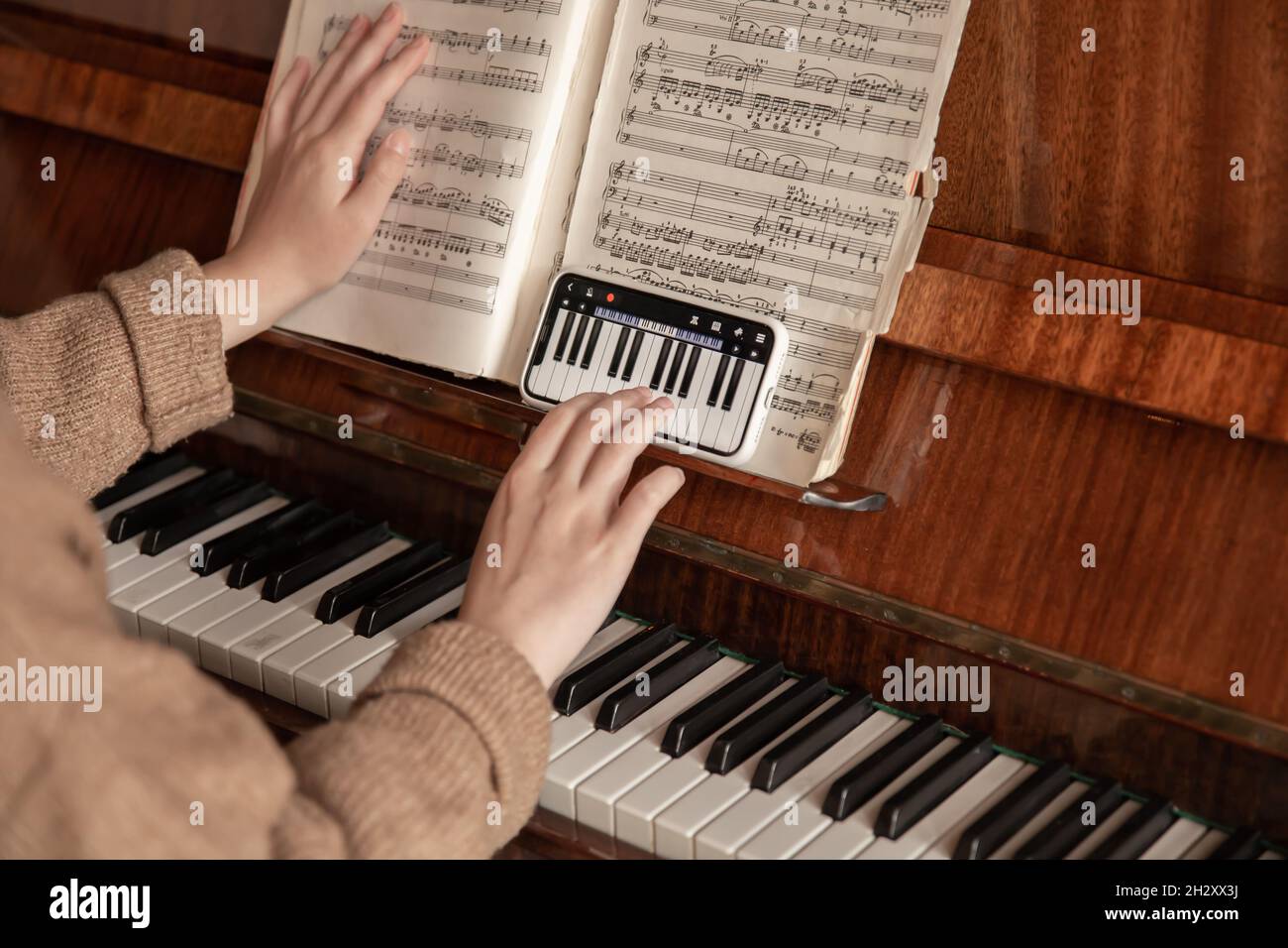 Une femme apprend à jouer du piano à l'aide d'une application sur son  téléphone Photo Stock - Alamy