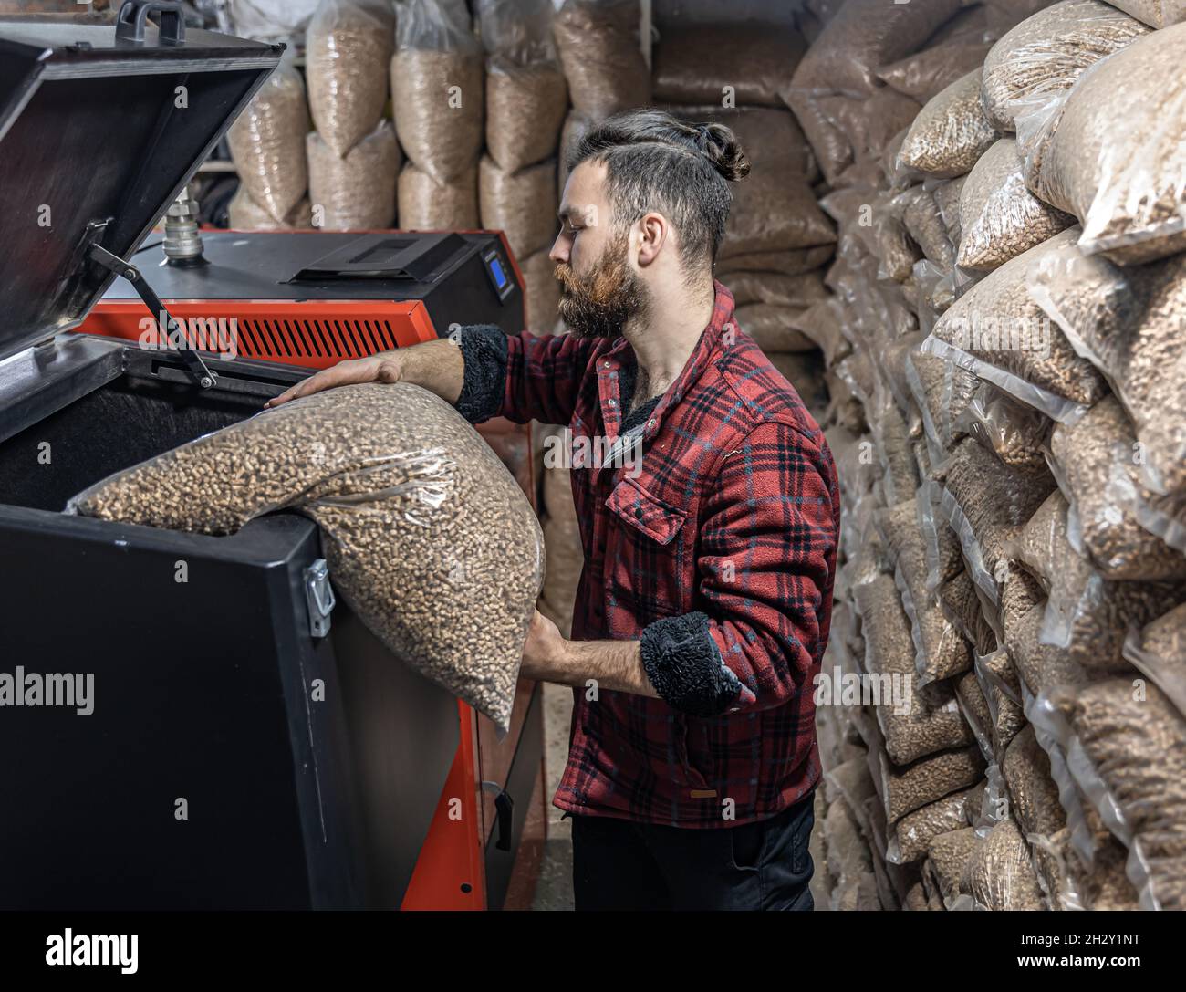 L'homme charge les granulés dans la chaudière à combustible solide, en travaillant avec les biocarburants. Banque D'Images