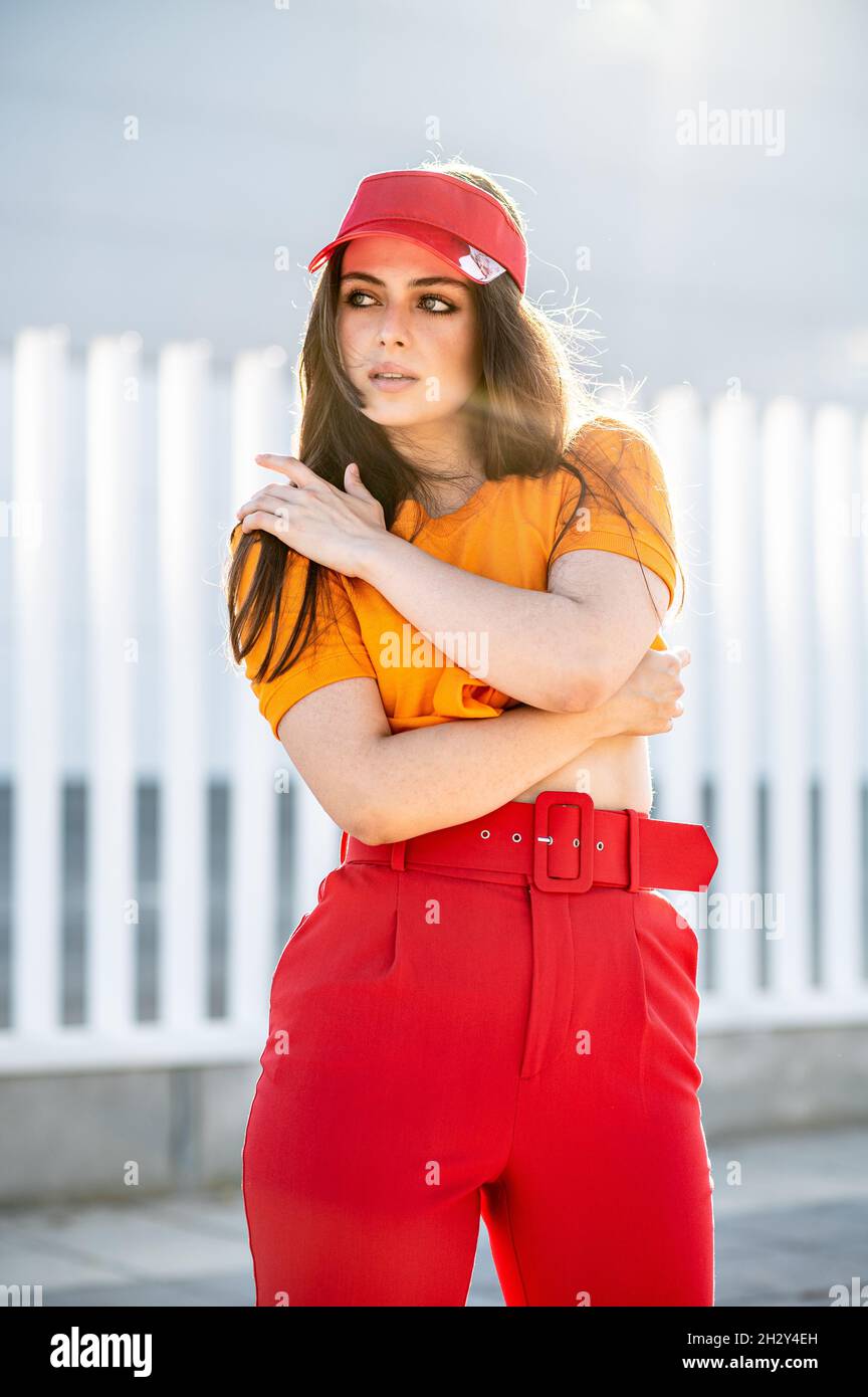 Une jeune femme élégante avec une casquette rouge et un pantalon posant  Photo Stock - Alamy