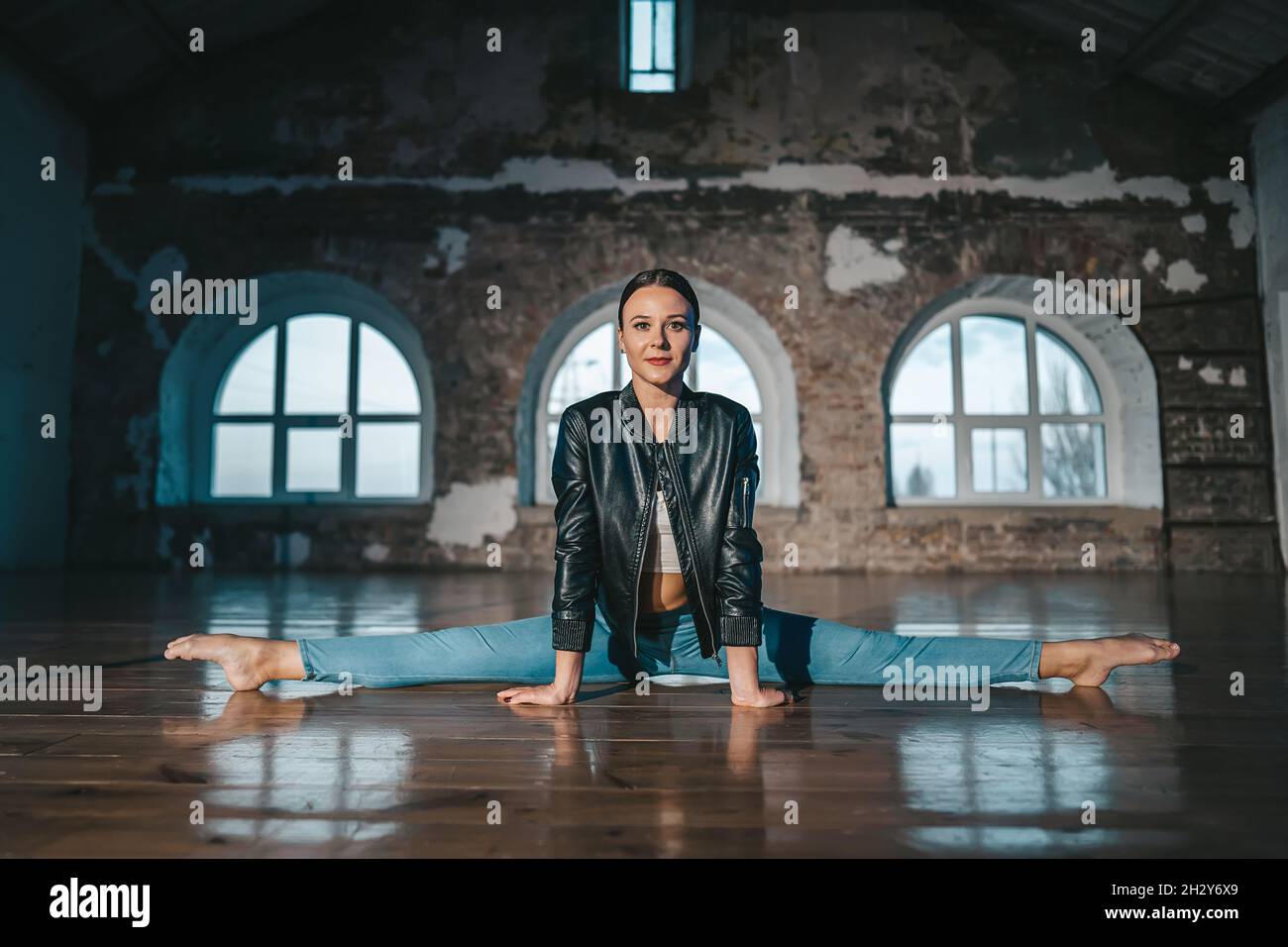 Danseuse de ballet contemporaine dans un style décontracté - Jean et veste de cuir assis dans la ficelle dans un studio moderne.Pratiques ballerines attrayantes seules Banque D'Images