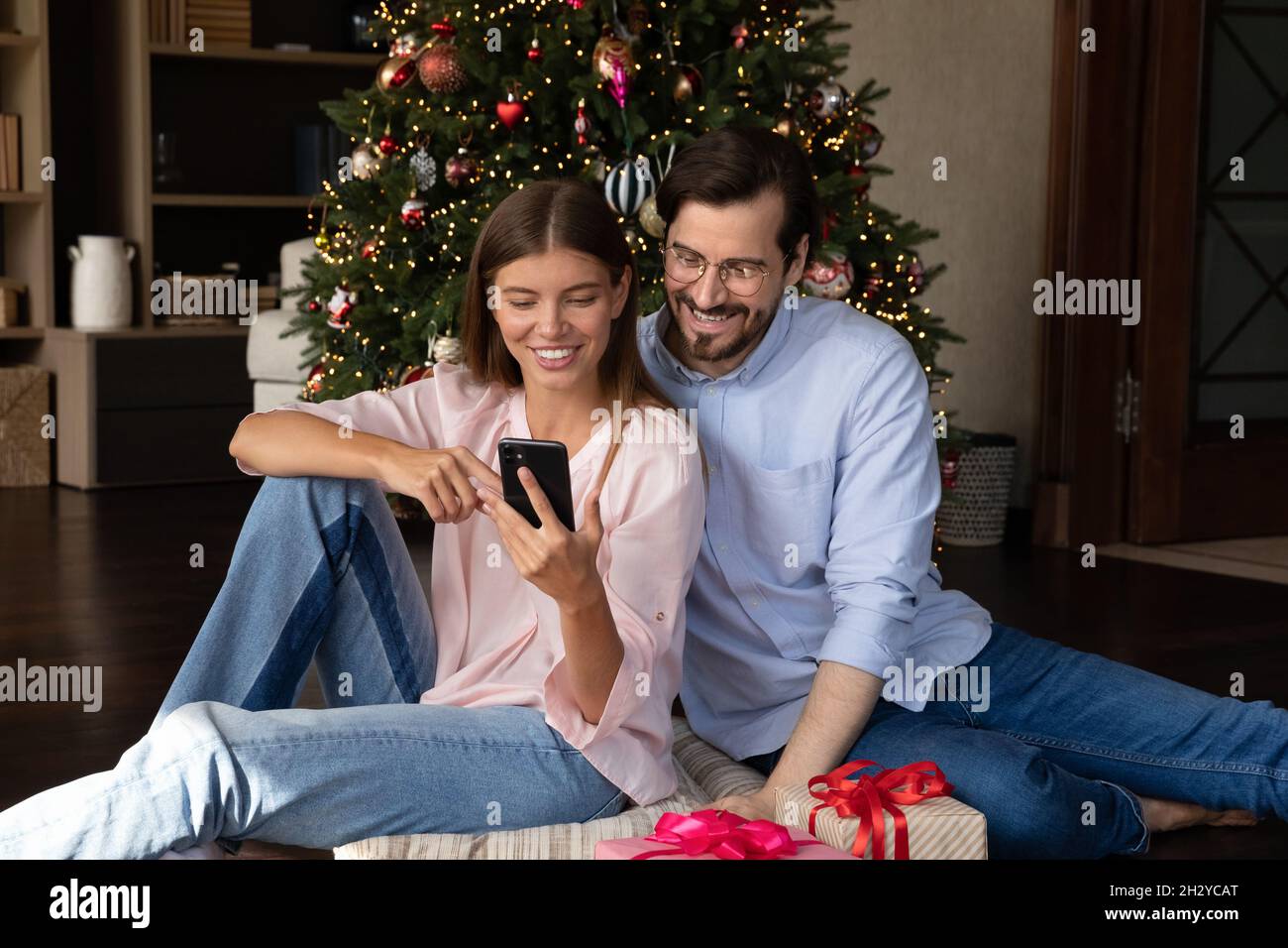 Un couple heureux et détendu en famille utilisant un smartphone à la maison. Banque D'Images