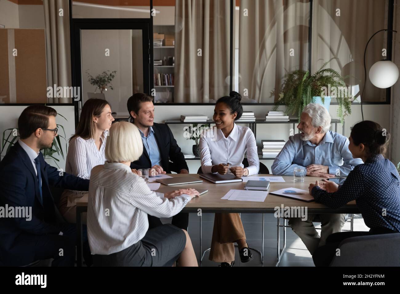 Le personnel multiethnique s'assoit à table et écoute les femmes expertes asiatiques Banque D'Images