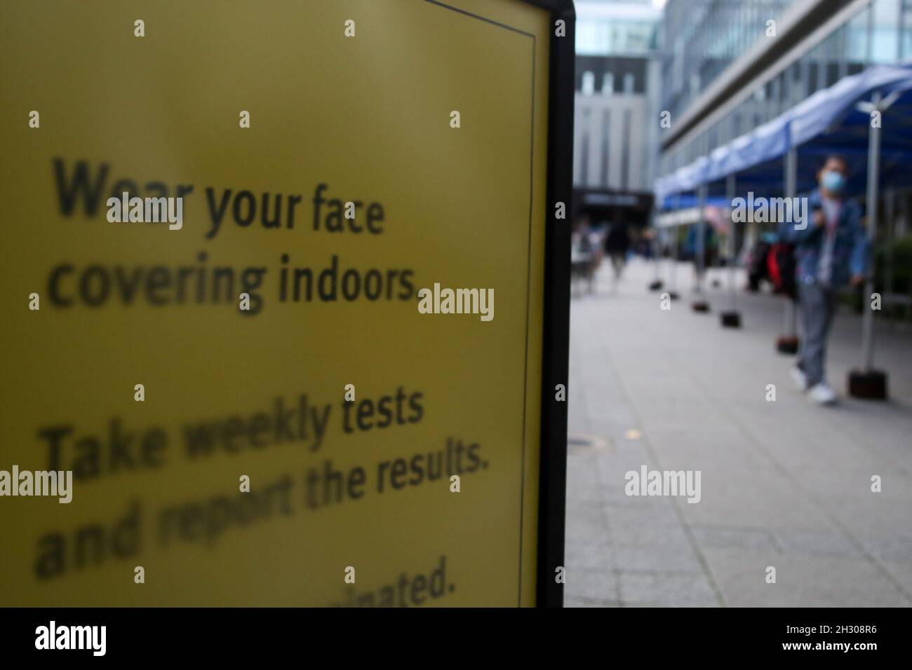 Londres, Royaume-Uni.20 octobre 2021.Une femme portant un masque facial comme mesure préventive contre la propagation du coronavirus se promène devant le signe « portez votre visage à l'intérieur » en London.Compulsory, le port de masques faciaux pourrait revenir cet hiver à mesure que les cas de coronavirus augmentent.Crédit : SOPA Images Limited/Alamy Live News Banque D'Images