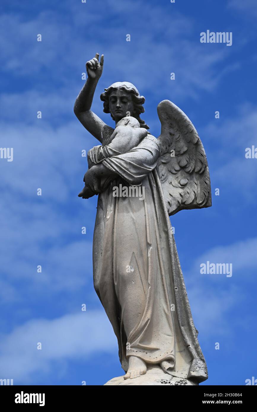 Une Sculpture En Pierre D Un Ange Un De Ses Doigts Casses Tenant Un Bebe Avec Ciel Bleu Et Nuages Blancs Clairs En Arriere Plan Photo Stock Alamy