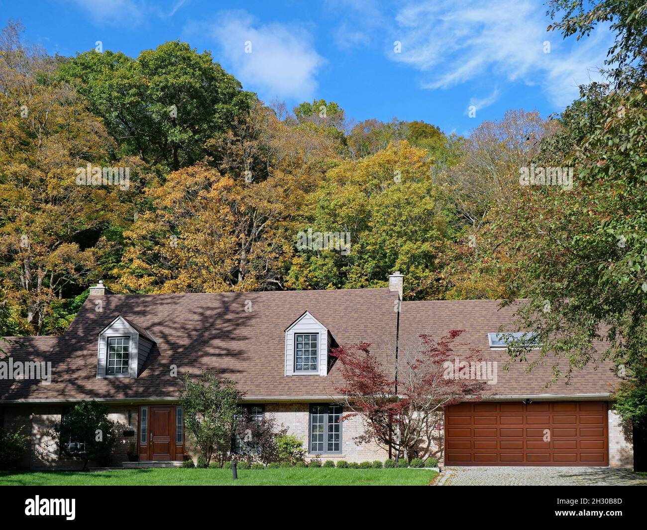 Maison de style ranch avec dortoirs et garage pour deux voitures, entourée d'arbres aux couleurs d'automne Banque D'Images