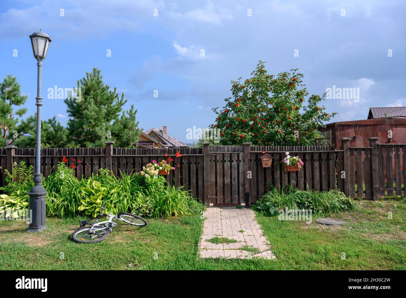 Une rue avec une clôture en bois, une lanterne, des fleurs et un vélo dans le village de Sviyazhsk en Russie Banque D'Images