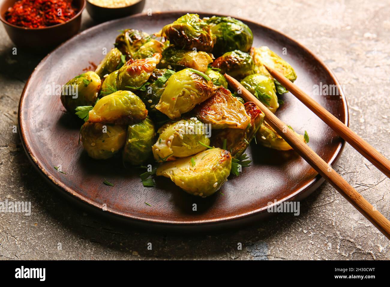 Assiette avec savoureux chou de Bruxelles rôti sur fond gris, gros plan Banque D'Images