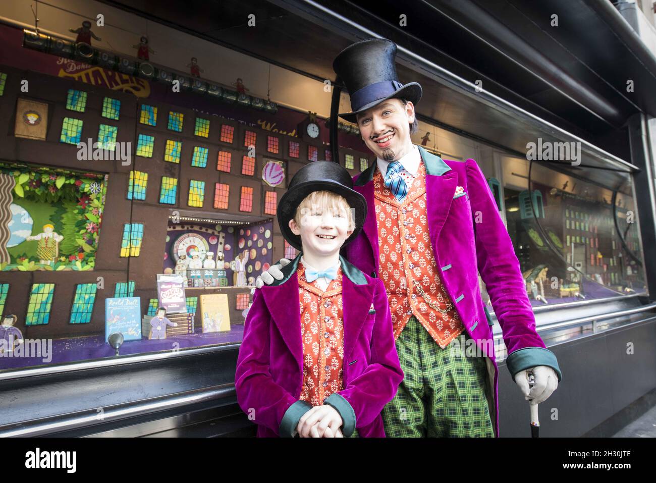 Willy Wonka (Ross Dawes) et Charlie (Troy Tipple) représentent un photocall devant une fabrique de chocolat en biscuit recréé par la comédie musicale West End et Biscuiteers, soutenus par Tate et Lyle, pour le 50e anniversaire de Charlie et de la chocolaterie Roald Dahl,Dans la vitrine Waterstones, Piccadilly, Londres. Banque D'Images