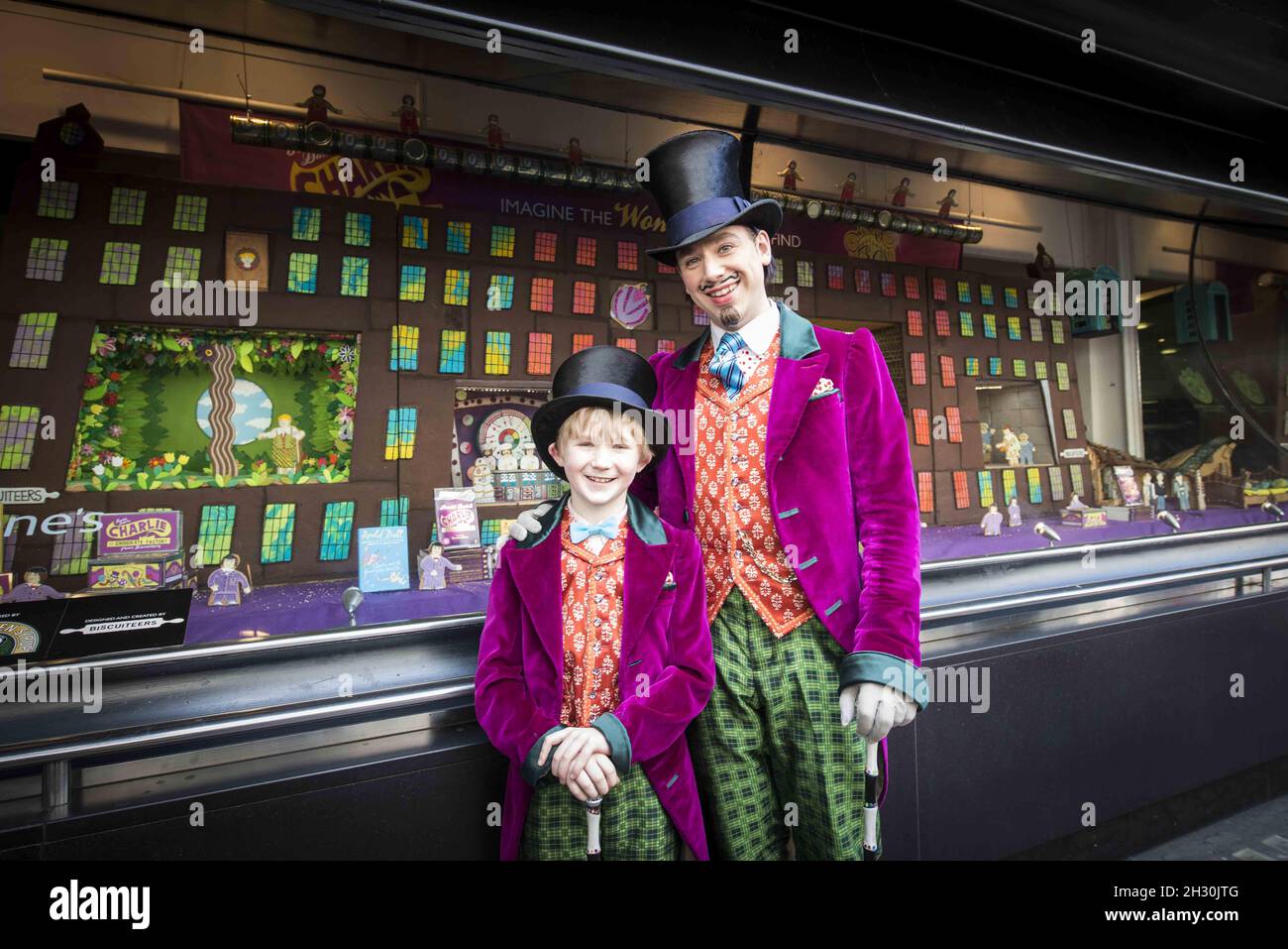 Willy Wonka (Ross Dawes) et Charlie (Troy Tipple) représentent un photocall devant une fabrique de chocolat en biscuit recréé par la comédie musicale West End et Biscuiteers, soutenus par Tate et Lyle, pour le 50e anniversaire de Charlie et de la chocolaterie Roald Dahl,Dans la vitrine Waterstones, Piccadilly, Londres. Banque D'Images