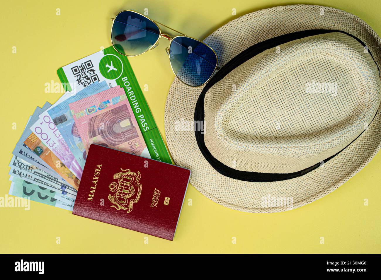 Concept de vacances.Présentation du passeport, de la carte d'embarquement, des lunettes de soleil, du chapeau de paille et de l'argent factice.Les gens sont prêts à partir en vacances après la longue pandémie Banque D'Images