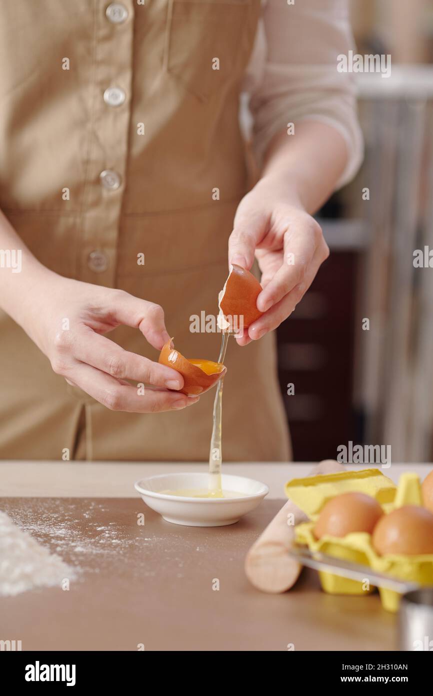 Processus de la jeune femme séparant le jaune d'œuf du blanc lors de la préparation de la pâte pour la pâtisserie Banque D'Images