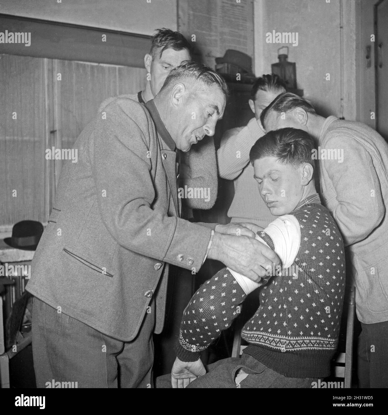 Männer legen einen Verband in einem Erste Hilfe Kurs an, Deutschland 1953.Les hommes apprennent à mettre en place un bandage dans une leçon de premiers soins, Allemagne 1953. Banque D'Images