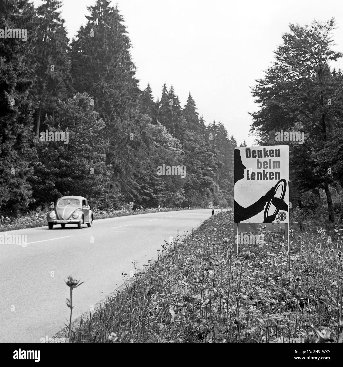 Warnschild 'denken beim LENKEN' am Straßenrand au Bayern, Allemagne 1959.Panneau de signalisation par une rue en Bavière, Allemagne 1959. Banque D'Images