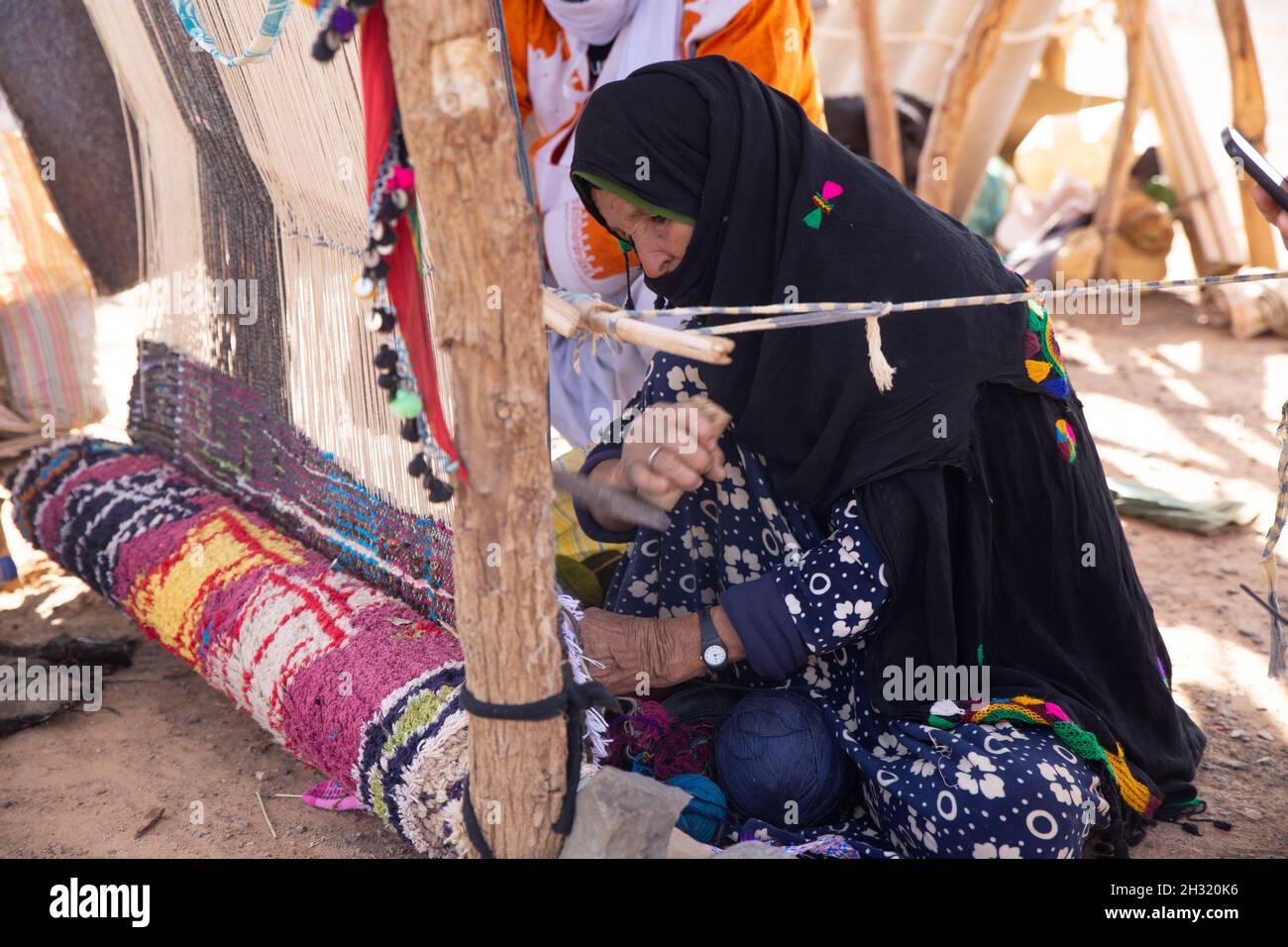 Une femme se serpente sur un métier à tisser traditionnel dans le désert du Sahara. Banque D'Images